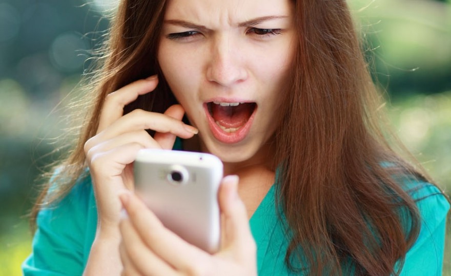 anxcios young girl looking at phone seeing bad news or photos there with disgusting emotion on her face